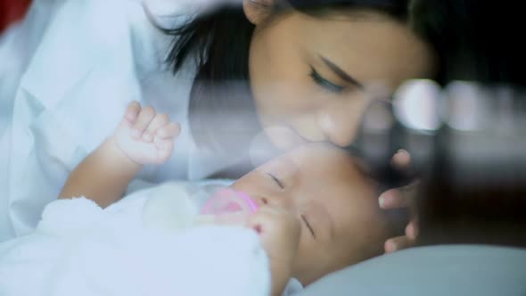 Asian Baby Sleep and Young Mother Kiss on Forehead