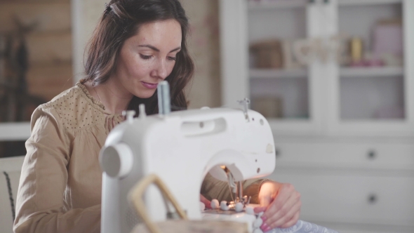 A Woman Sitting at a Modern Sewing Machine Enjoying Crafts and Hobbies