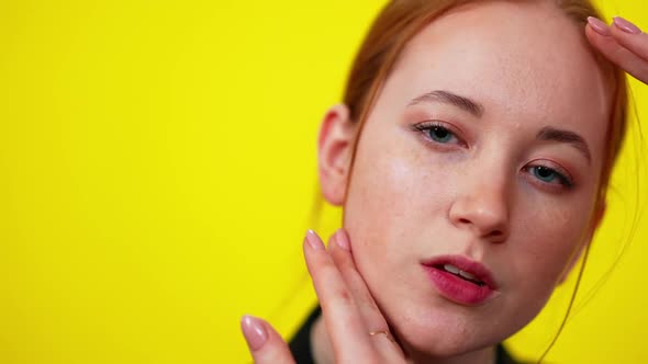 Closeup Face of Freckled Redhead Slim Caucasian Woman on the Right Touching Cheek with Hand Looking alt