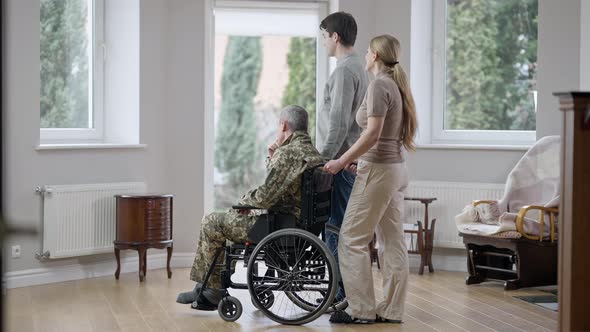 Side View Wide Shot of Caucasian Family Looking Out the Window Talking alt