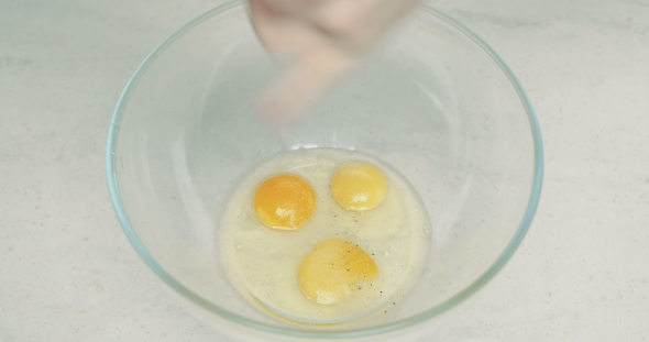 Beaten Eggs Being Sesoned with Pepper and Salt alt