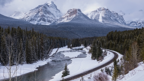 Train Tracks Next To River in the Mountains with Snow Falling, Stock ...