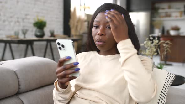 Disappointed Young AfricanAmerican Woman Holding Smartphone
