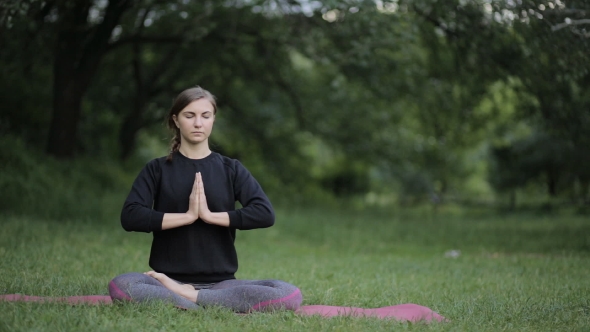 Young Girl Doing Yoga and Meditating at Sunset