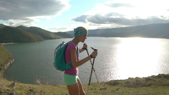 Young Woman with Backpack Walking Round Mountains and Lake