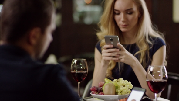 Couple Using Smartphone During Dating in Pompous Cafe