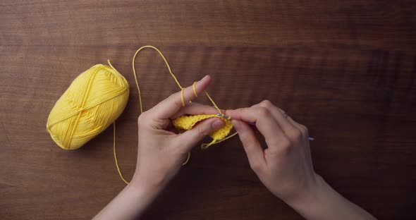 Time-lapse of the crocheting process. Caucasian hands grabbing a yellow piece of wool and starting t alt