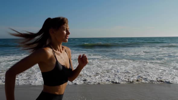 Athletic woman jogging along the beach alt