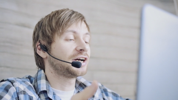 Friendly Young Call Center Worker with Headset Talking with Client in Agency