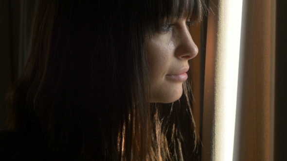 Female Peeking Out From Behind the Curtains