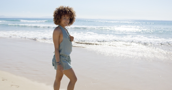 Female Wearing Jumpsuit Walking Along Beach alt
