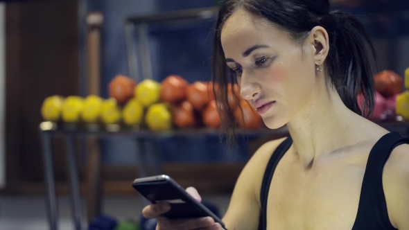 Woman Sitting Inside Gym, Looking in Phone, Relaxing alt