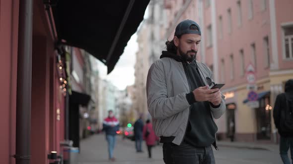 Young Modern Handsome Man Talking on the Phone on the Street of a Small Town alt
