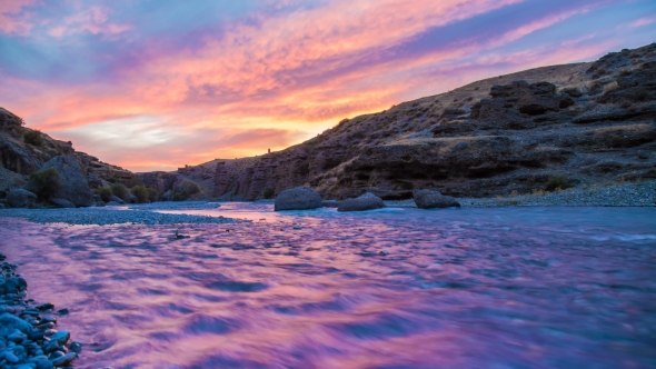 . The Flow of a Wide River in the Canyon at Sunset