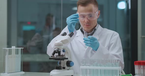 Young Chemist Expert Is Experimenting in Laboratory, Mixing Substance and Liquids in Test Tube alt