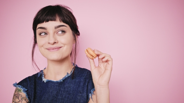 Attractive Brunette Eats Macarons Isolated on Bright Backgrounds alt