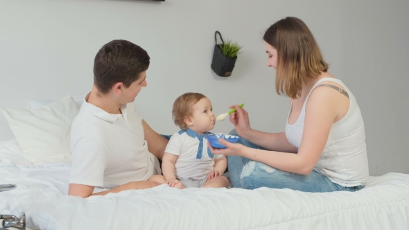 VideoHive Young Parents Feed Baby on a White Room Happy Family 19622214 VideoHive Young Parents Feed Baby on a White Room Happy Family 19622214