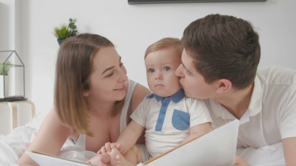 VideoHive Mom and Dad Kissing Their Baby Lying on the Bed 19622251 VideoHive Mom and Dad Kissing Their Baby Lying on the Bed 19622251