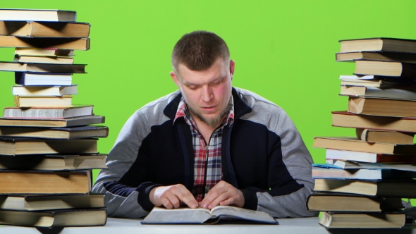 Man Sitting at the Table Reading, Finding Information and Happy. Green Screen alt