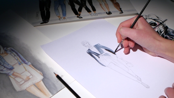 Designer Dresses Painted on a Sketch on a Table at Her Lie Many Other Sketches. alt