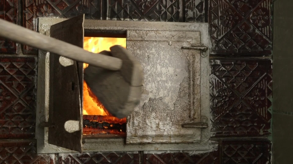 Cook Opens the Door to the Oven and Adjusts Fire