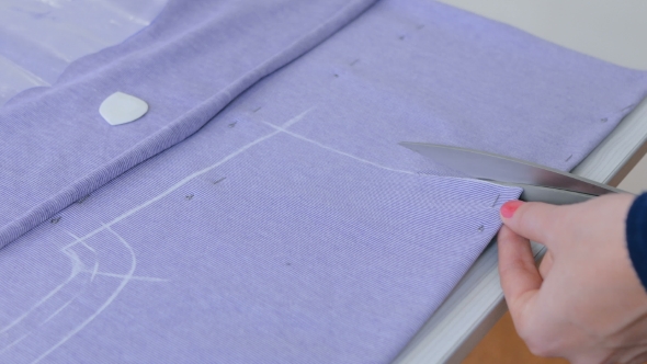 Hands of Seamstress Cutting Fabric with Scissors