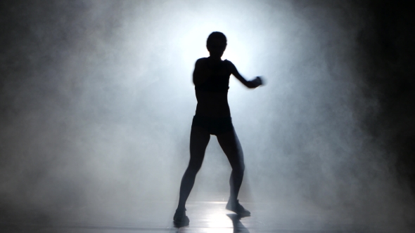 Girl Kickboxer Gloves Sends the Punches. Silhouette. Black Background. Lights Rear alt