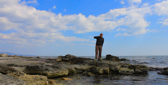 Man Talking On Mobile Phone On A Rocky Beach
