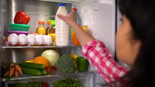 Woman Takes Milk From Fridge