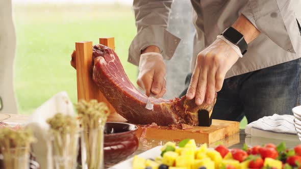 a Man in Gloves Cuts Into Thin Pieces of Dried Meat for a Banquet alt
