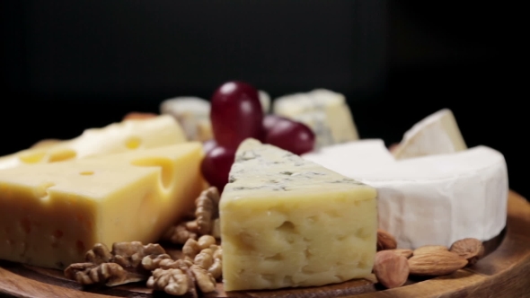 Cheese Platter with Nuts and Grapes on the Table