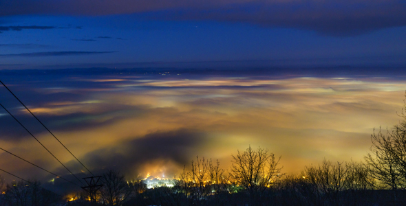 Day to night timelapse of foggy city during sunset