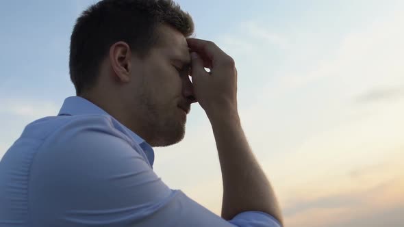 Sorrowful Man Thinking About Problems in His Life on Background of Evening Sky