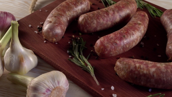 Raw Sausages with Garlic, Rosemary on Wooden Surface