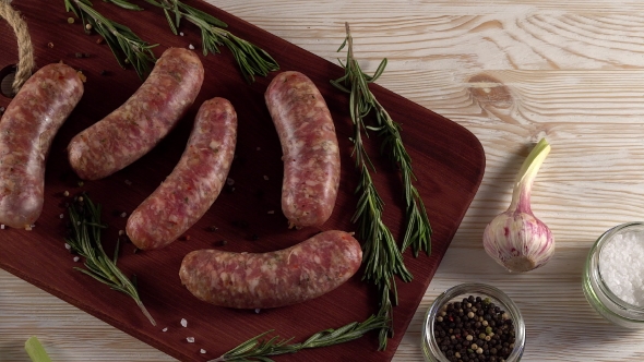 Raw Sausages with Garlic, Rosemary on Wooden Surface