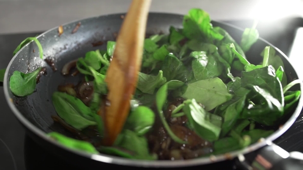 The Cook Makes Vegetable Dish with Onion Fried in Balsamic Vinegar and Adds Spinach alt