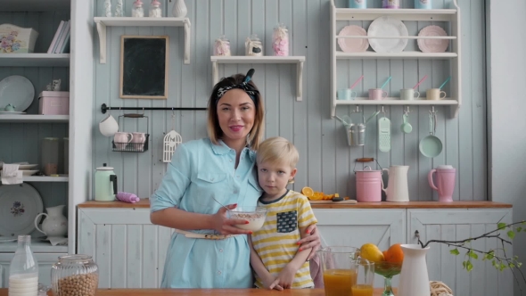 Adorable Little Boy Eating Corn Flakes in Kitchen with Mom, Young Mother and Child Breakfast, Happy alt