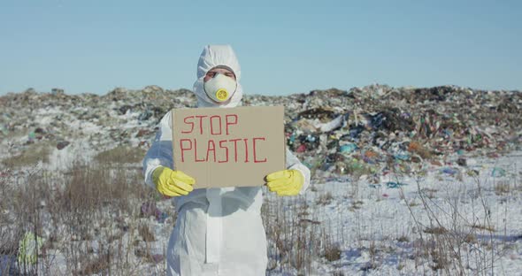 Man Wore in Protective Suit Show Protest Sign "Stop Plastic" at Plastic Landfill alt