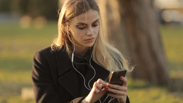 Young Attractive Girl Is Resting in the Central Park Sitting 
