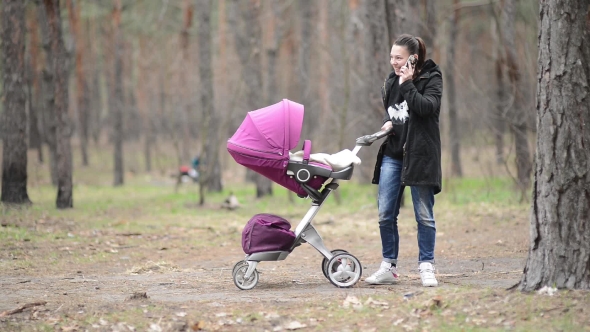 Mother Walking with a Baby Stroller In the Forest