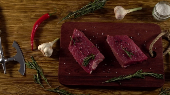 Beef Fillet on a Desk with Pepper, Rosemary Axe and Garlic.