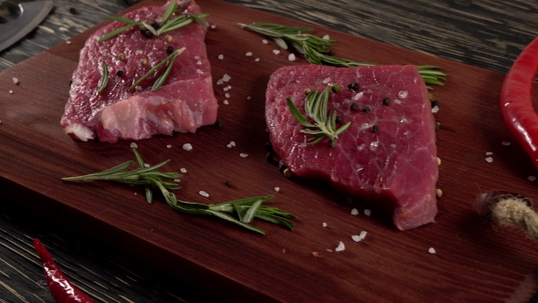 Beef Fillet on a Desk with Pepper, Rosemary Axe and Garlic.