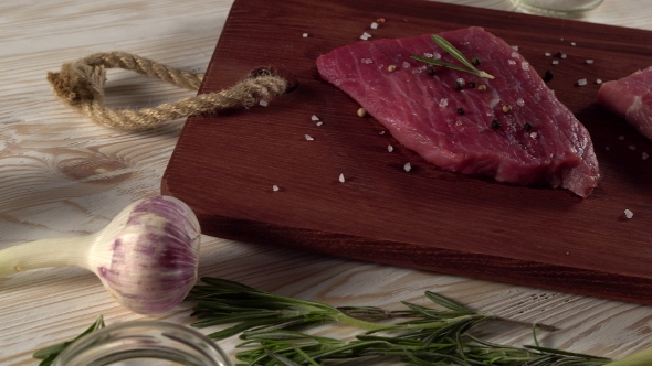 Beef Fillet on a Desk with Pepper, Rosemary Axe and Garlic.