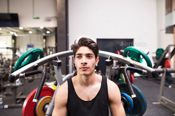 Hispanic man in gym prepared for training on fitness machine.