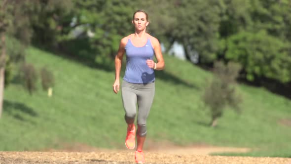 A woman running on a wood chip trail alt