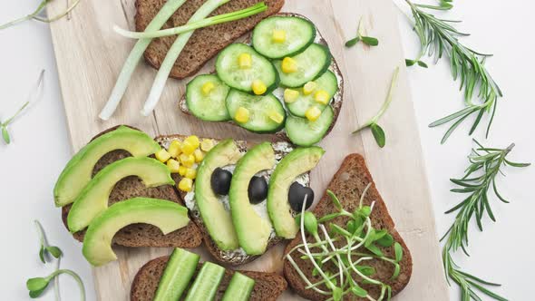 Sandwich with Avocado Cucumber Olives and Green Onions on a Wooden Board alt