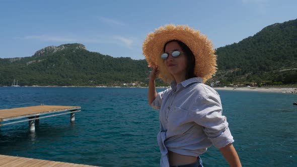 Young Sexy Girl in a Hat and Shorts Walking on the Pier alt