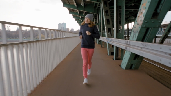 Young Woman Running Over the Industrial Bridge in the City alt