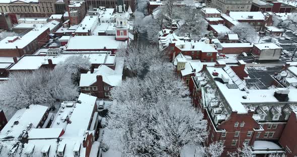 Rising aerial of American city in winter scene. Fresh snow covered trees. Pretty evening setting. Ca alt