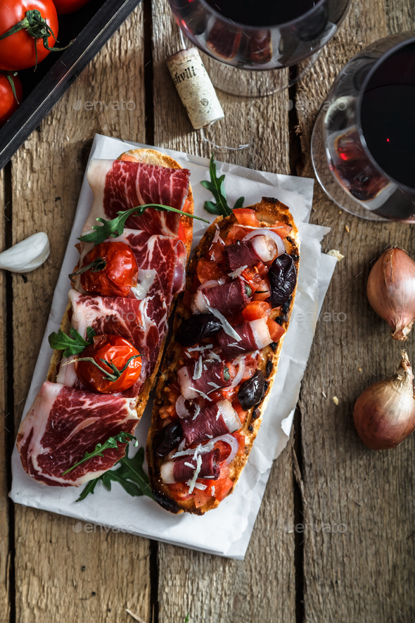 Variety of small sandwiches with jamon, tomatoes, parmesan cheese, fresh basil served with wine - Stock Photo - Images